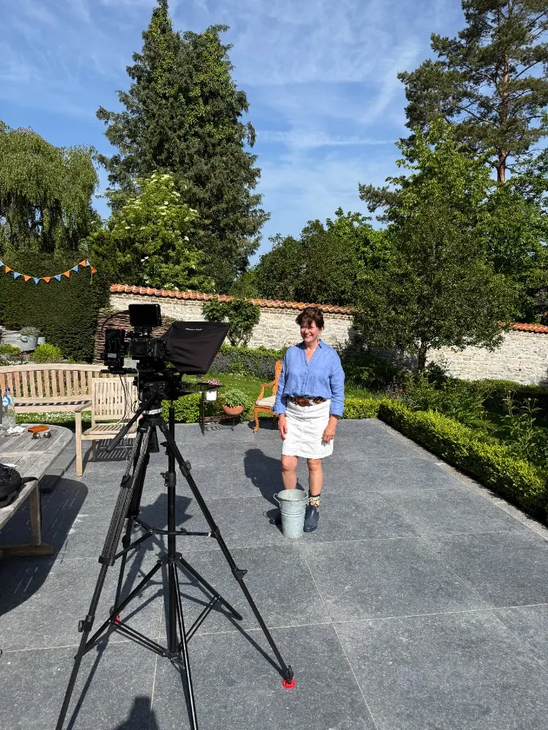 Camera on a tripod filming a woman on a garden terrace