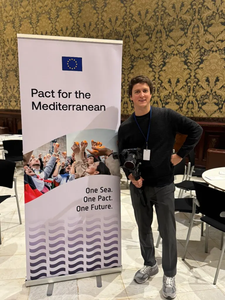 Antoine Similon with a camera gimbal beside a Pact for the Mediterranean banner