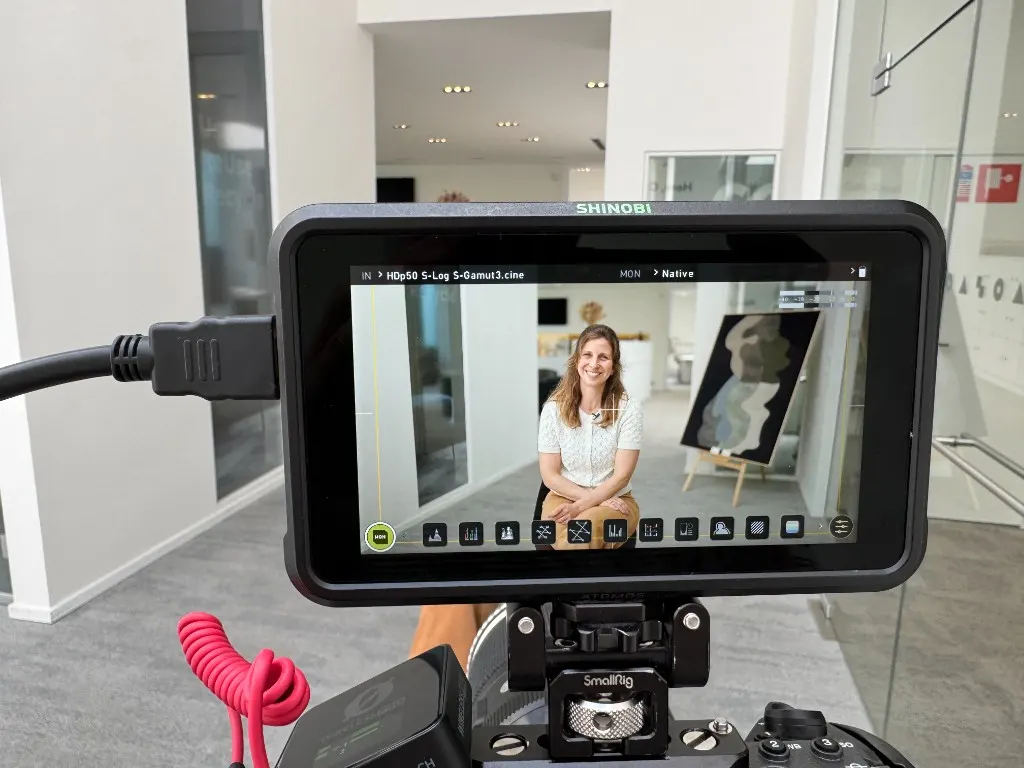 Camera monitor showing a live interview in a bright Brussels office
